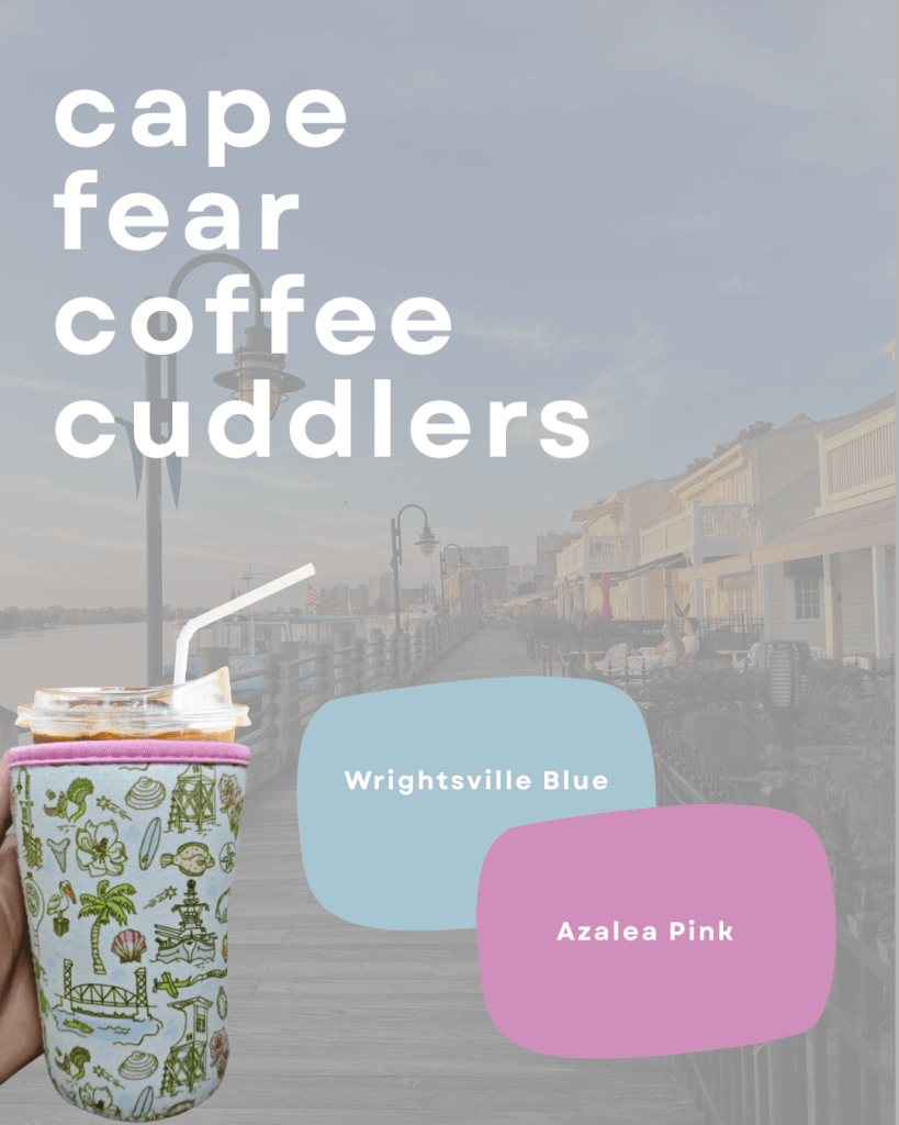 Image of a Cape Fear Coffee Cuddler in two colors, Wrightsville Blue and Azalea Pink, held by a person. A scenic waterfront boardwalk is in the background.