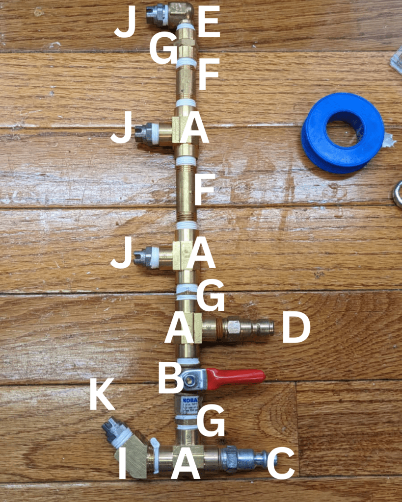 Image showing a snowmaking setup with various brass fittings, valves, and a roll of Teflon tape on a wooden surface.