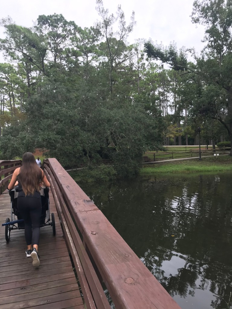 Girl pushes baby stroller over bridge