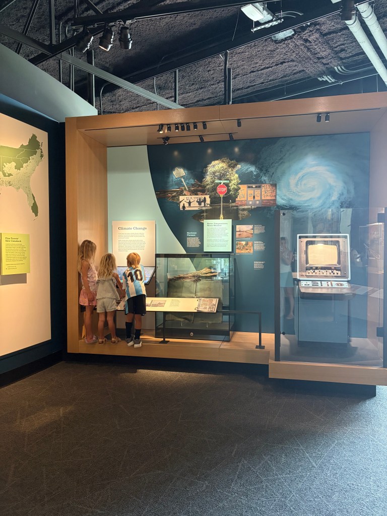 Children exploring a museum exhibit about climate change, with interactive displays and informational panels.